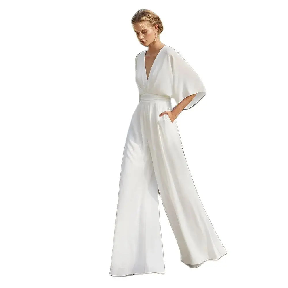 Studio product cutout on a plain white background displaying the full silhouette of the elegant white wide-leg wedding pantsuit with its plunged V-neckline and flutter sleeves.