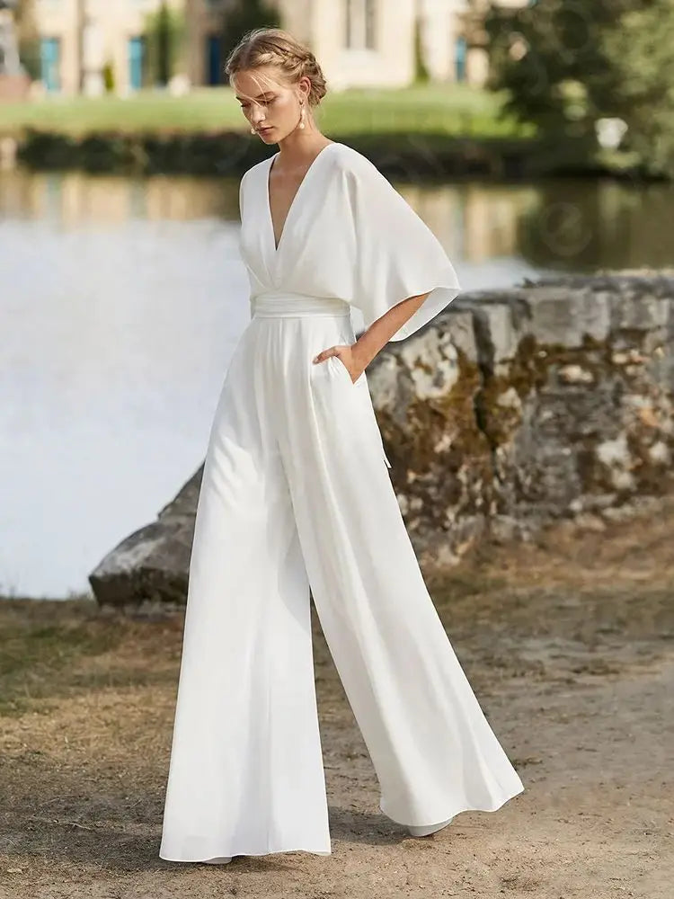 Full-length walking view of the minimalist white bohemian wedding dress jumpsuit, emphasizing the fluid movement and elegant drape of the wide-leg pants.