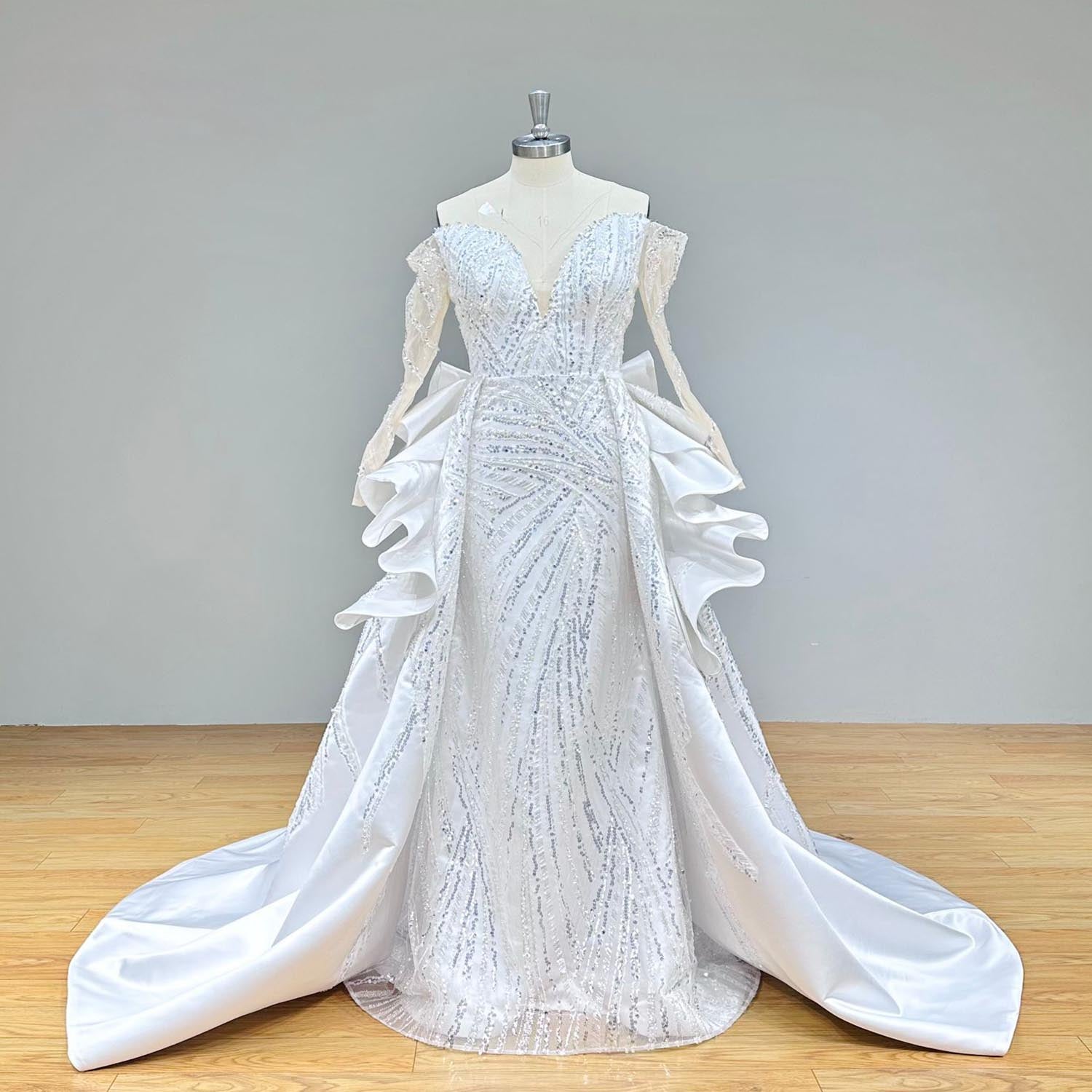 Angled profile of a luxury mermaid wedding dress on a studio mannequin, capturing the detailed beadwork on the sleeves and the seamless detachable train attachment.