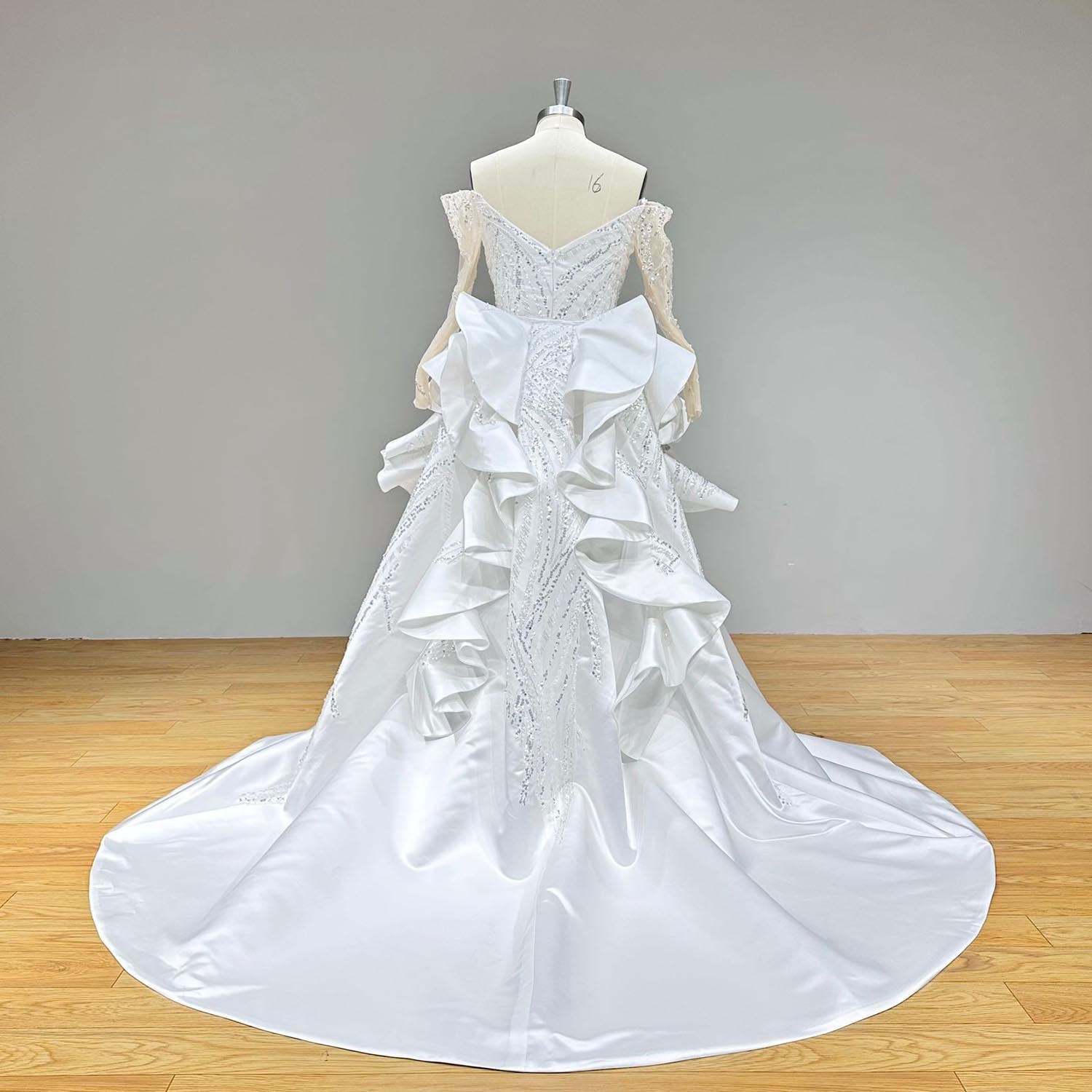 Back view of a mermaid wedding dress on a mannequin, showcasing the illusion lace back, intricate beadwork, and the full length of the detachable cathedral train.