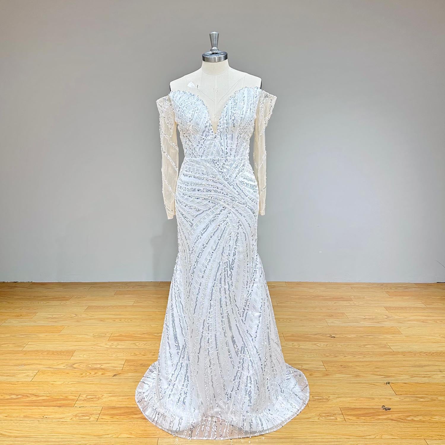 Three-quarter side angle of an off-shoulder long sleeve mermaid wedding gown on a mannequin, emphasizing the flattering silhouette and beaded lace appliqué details.