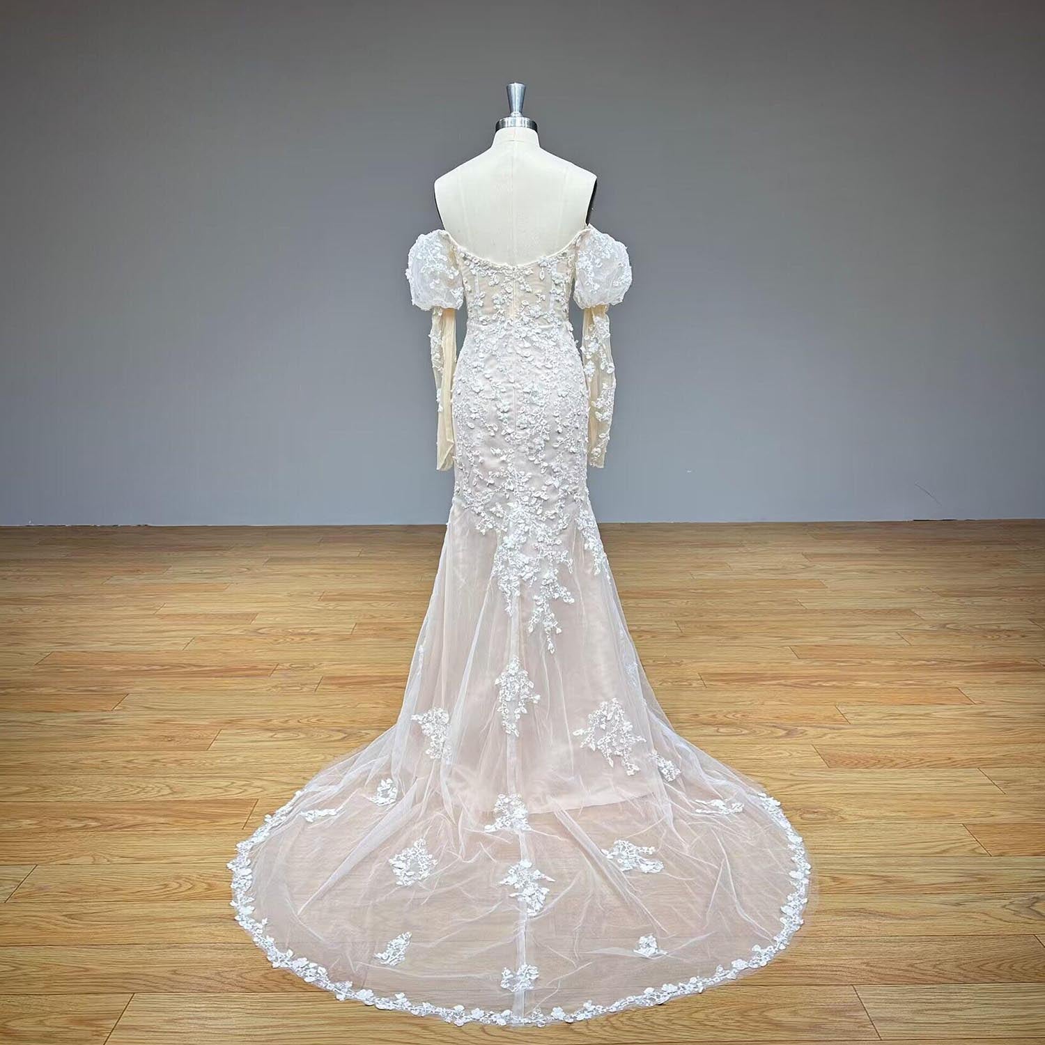 Full back display of the off-the-shoulder mermaid wedding dress on a mannequin, showcasing an expansive scallop-edged lace cathedral train pooling on the floor.