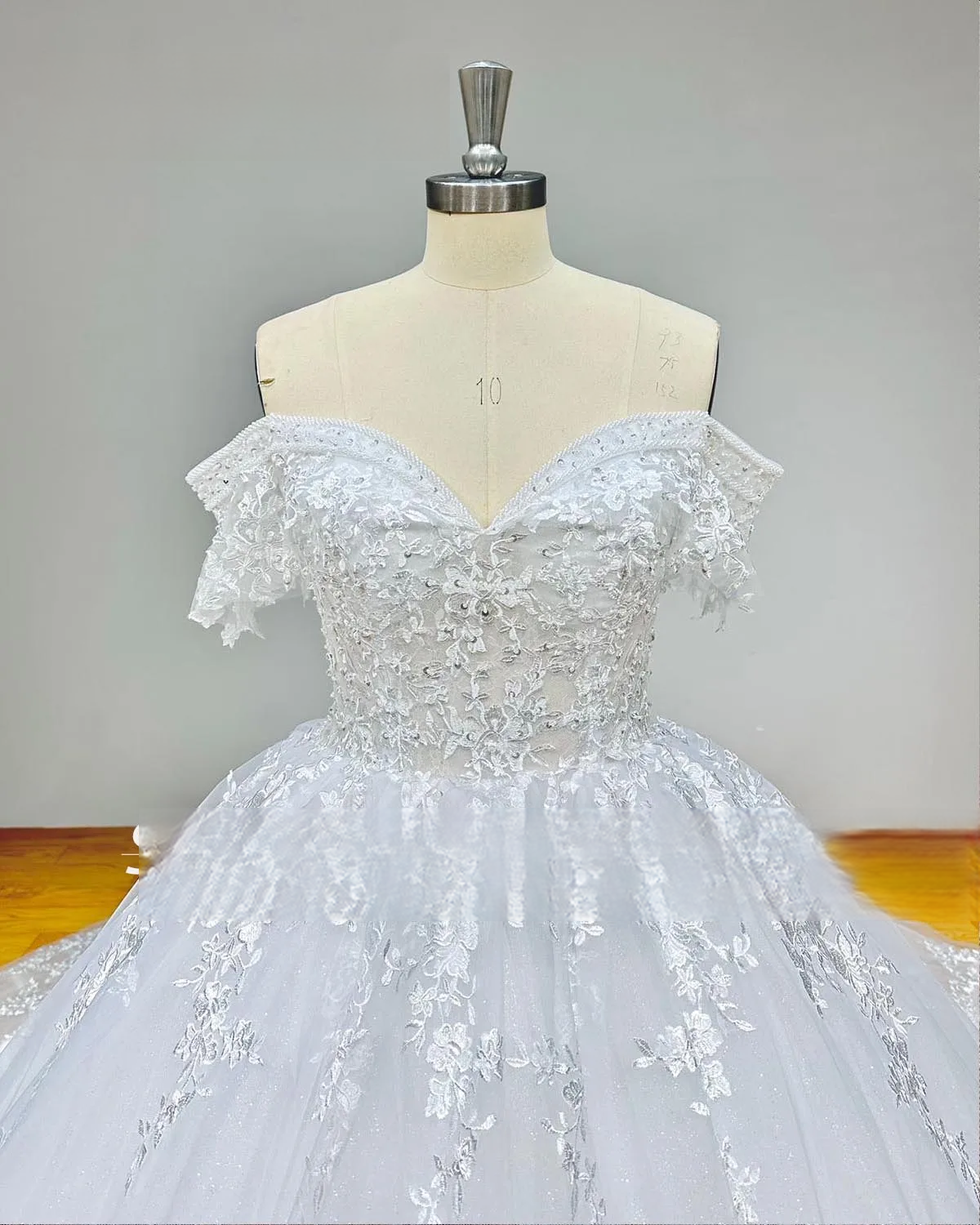 Close-up detail of the bodice on an off-shoulder sequin beaded ball gown wedding dress, highlighting the premium crystal beadwork and delicate lace appliqués.