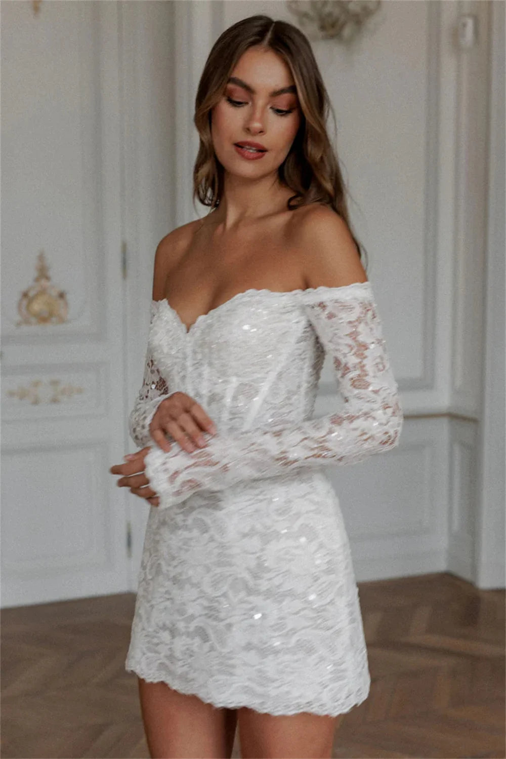 Romantic off-the-shoulder lace applique mini wedding dress featuring long sheer sleeves, a structured sweetheart corset bodice, and delicate shimmering sequin details.