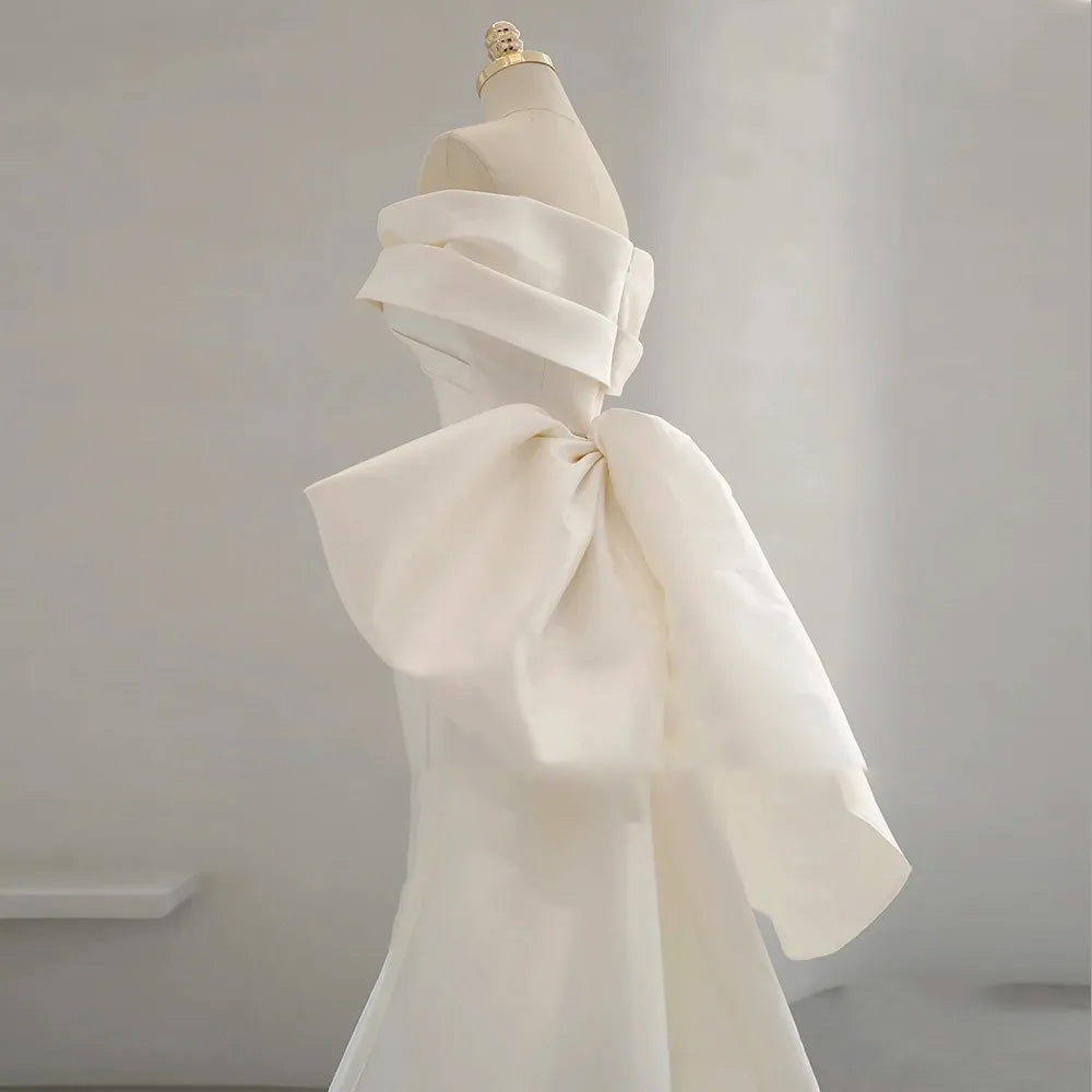 Rear view of an elegant off-the-shoulder mermaid wedding dress on a mannequin, highlighting the fitted silhouette and subtle train.