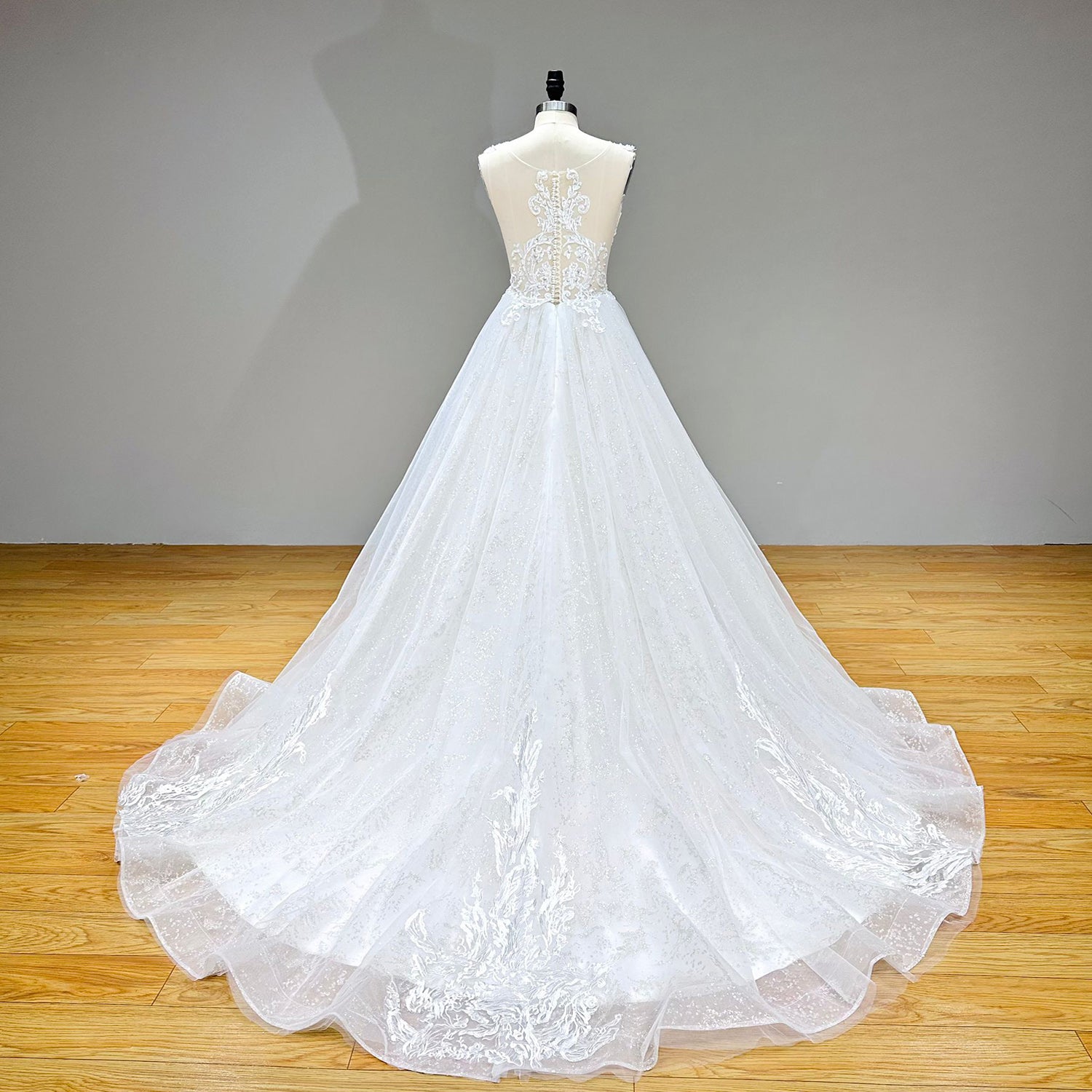 Full back view of the A-line wedding dress showcasing the sheer illusion back, intricate lace embroidery appliques, and a long tulle train.
