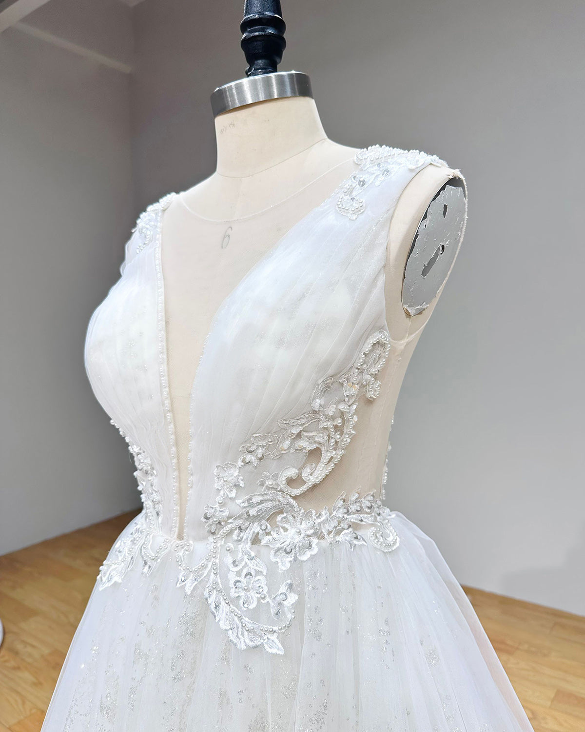 Side profile detail of the wedding dress bodice showing the sheer illusion side cutout adorned with silver embroidery and pearl embellishments.