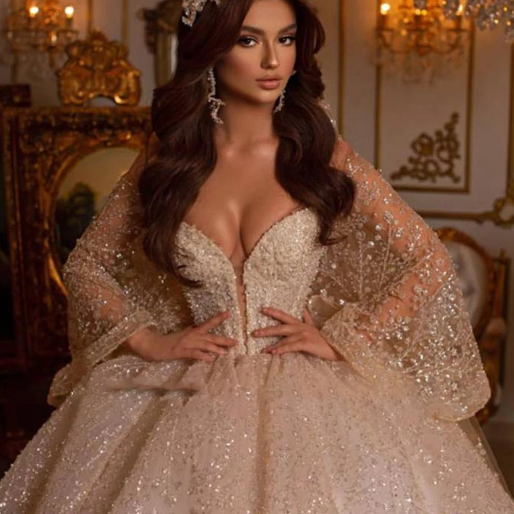 Rear view of a luxury princess bridal gown showcasing a low V-cut back, sparkling off-shoulder strap bands, and an expansive cathedral-length glitter tulle train.