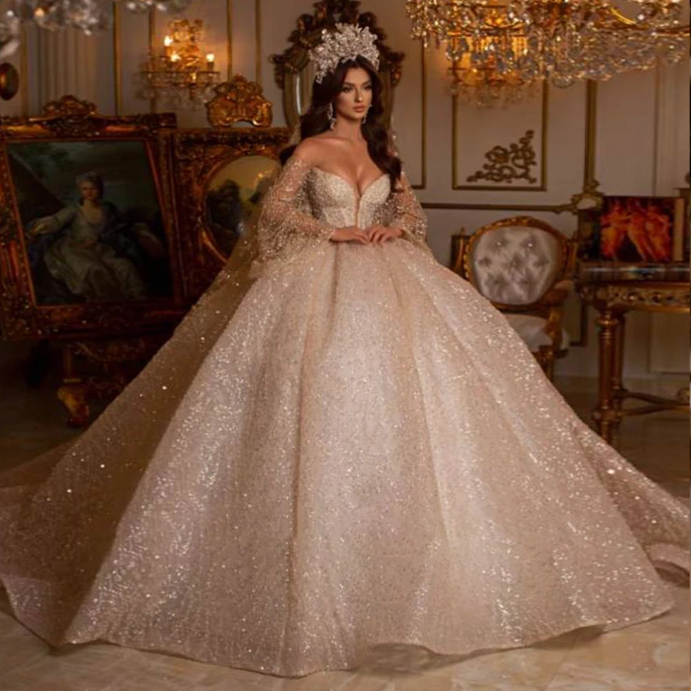 Stately pure white off-the-shoulder princess wedding dress completely covered in reflective silver glitter textures with a majestic tiered ballgown skirt.