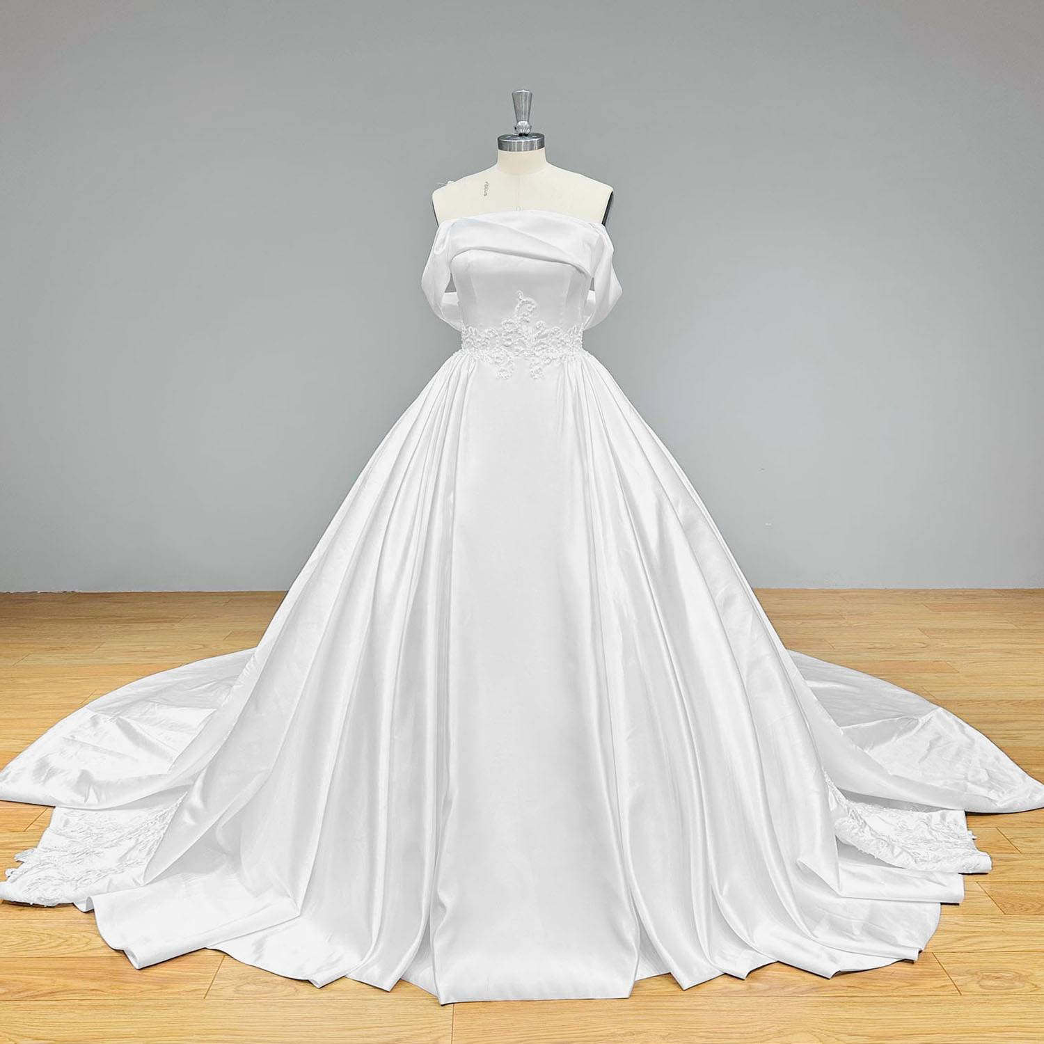 Classic heavy satin off-the-shoulder wedding dress with a structured sweetheart bodice and a voluminous pleated A-line skirt.