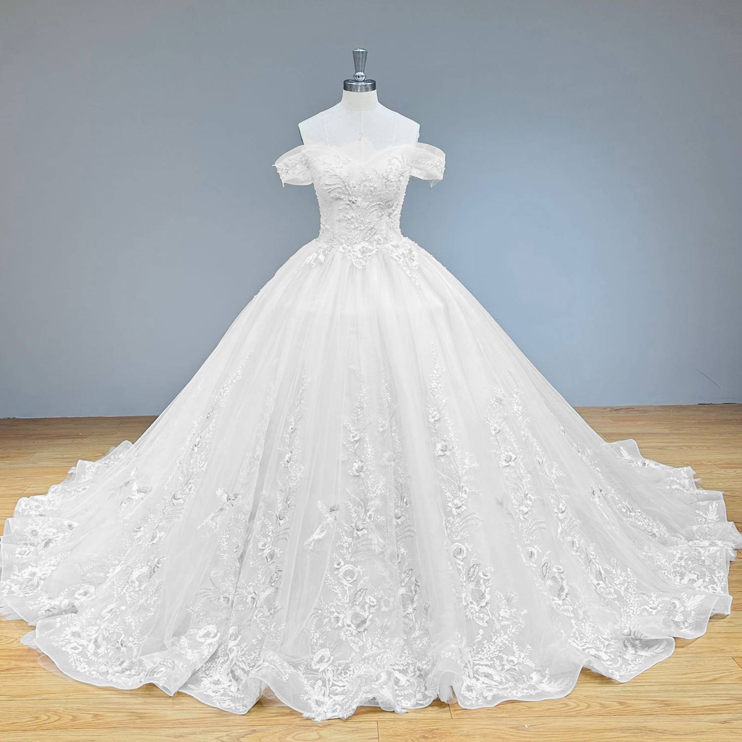 Full front view of a luxury champagne tulle ball gown wedding dress with gold embroidered appliques on a showroom mannequin.