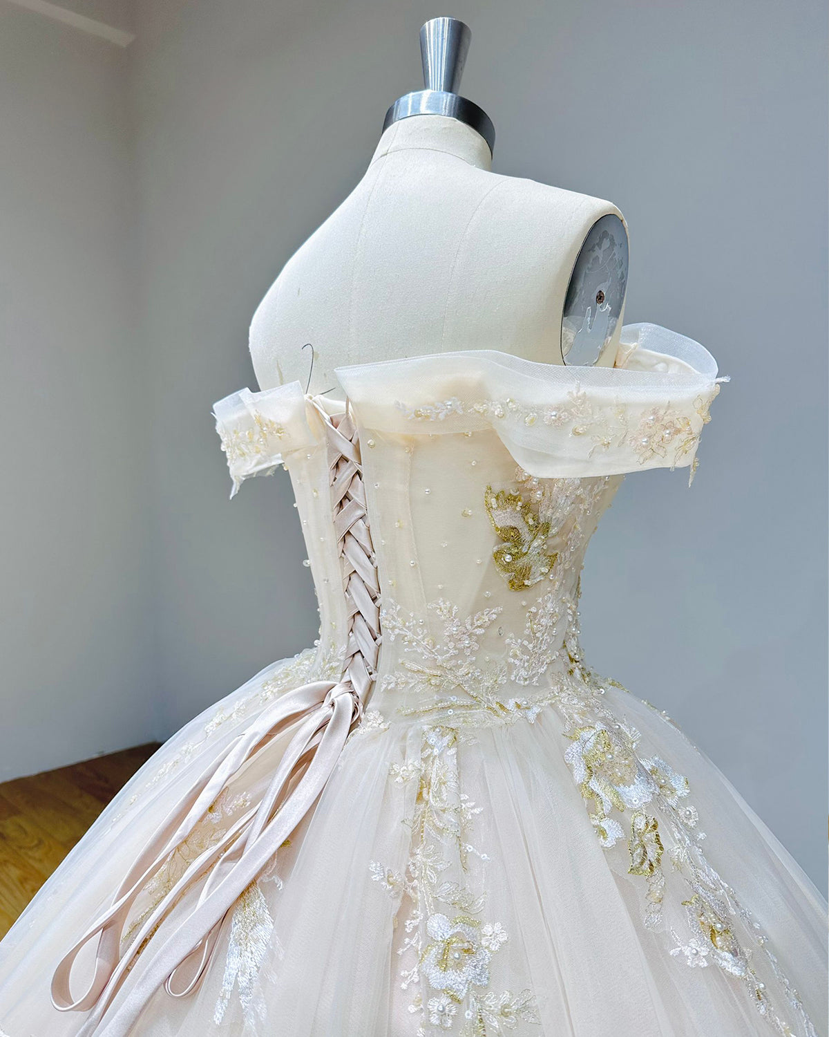 Side view detail of the adjustable satin ribbon lace-up back closure on a structured corset wedding dress bodice.
