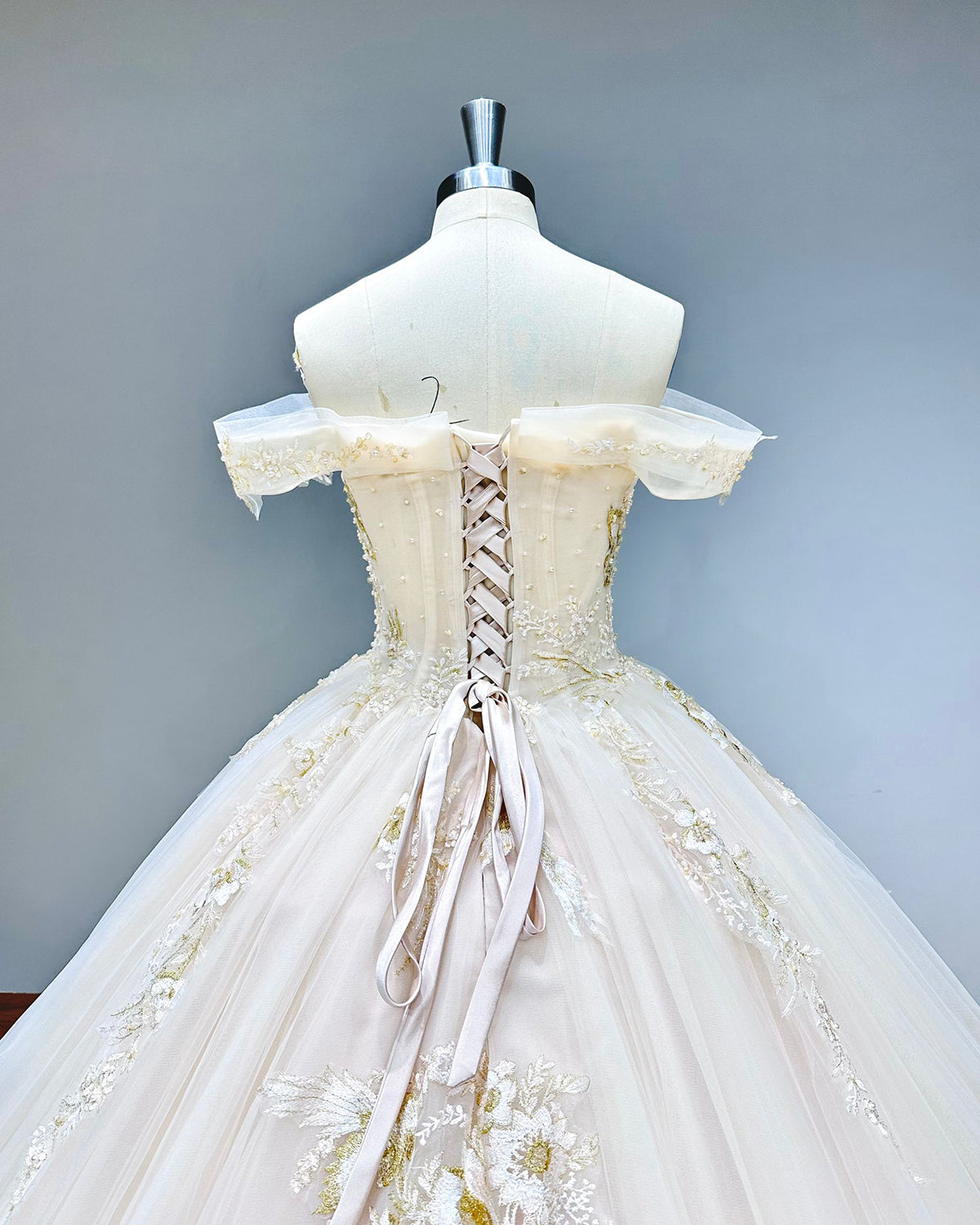 Close-up back view of a princess bridal gown showcasing the classic corset back design over a sheer illusion panel with boning details.