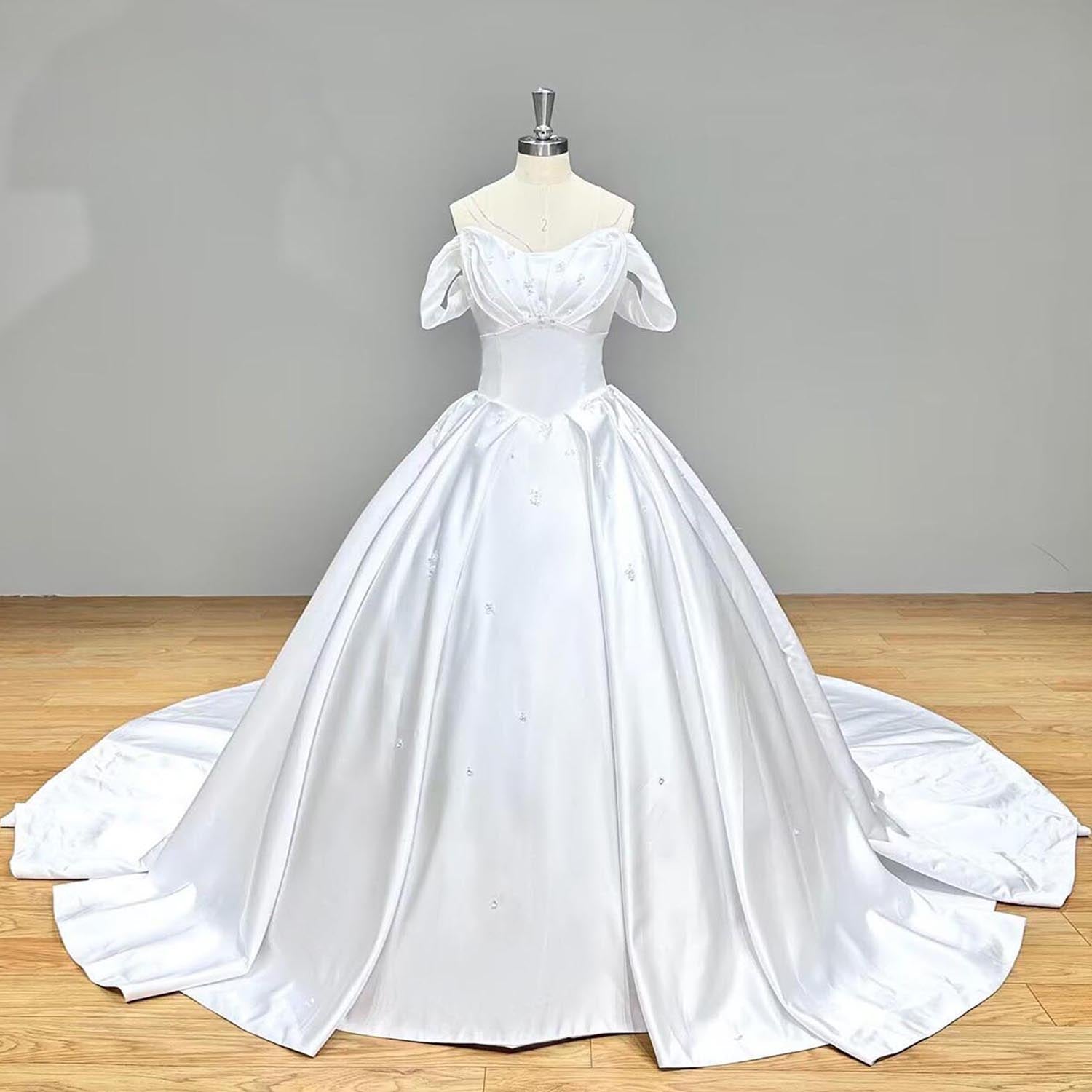 Full front view of a minimalist white satin princess ball gown bridal dress with subtle scattered crystal bead embroidery on a studio dress form.