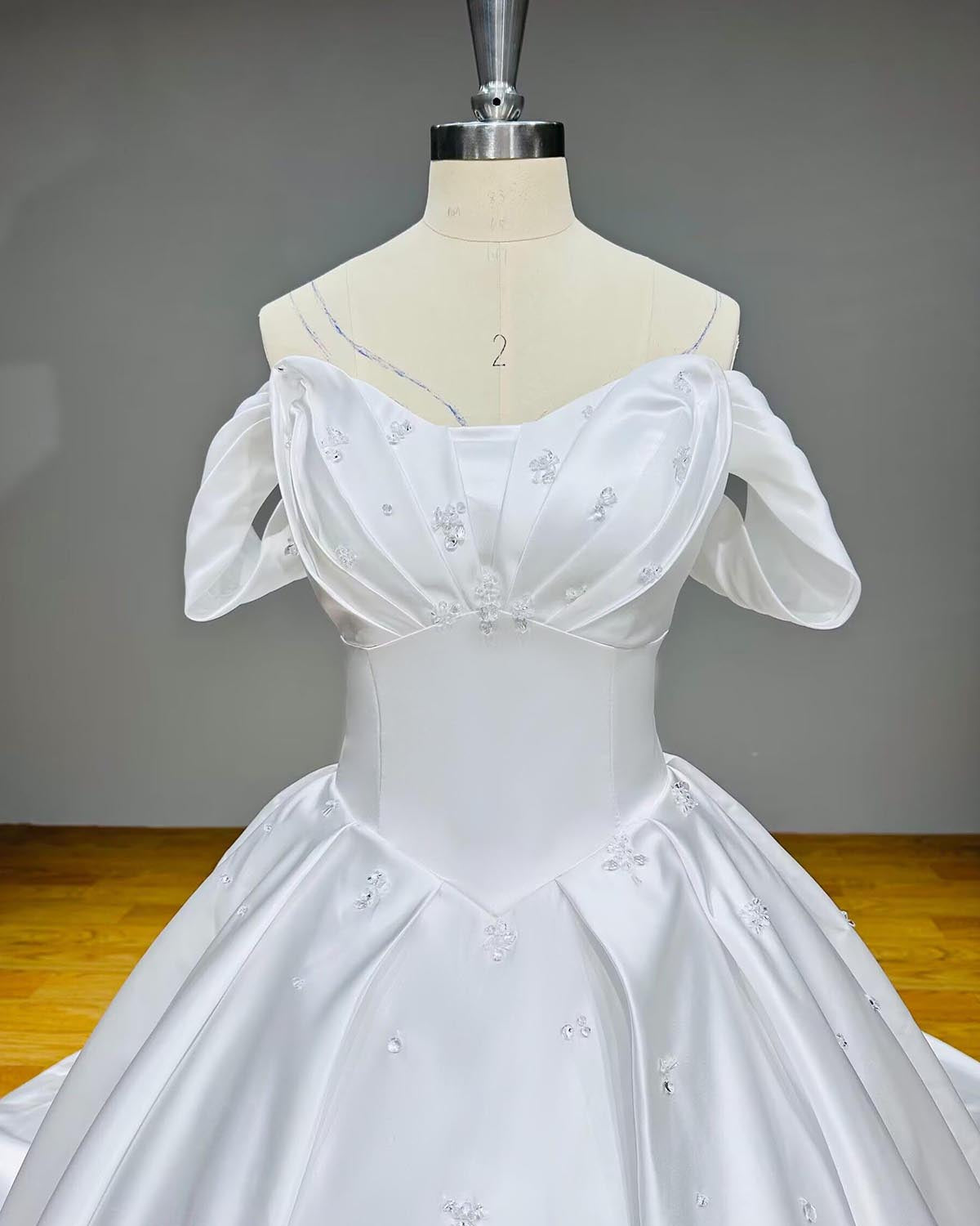 Front view close-up of a structured satin bridal bodice showcasing a pleated sweetheart neckline and seamless basque waist tailoring.