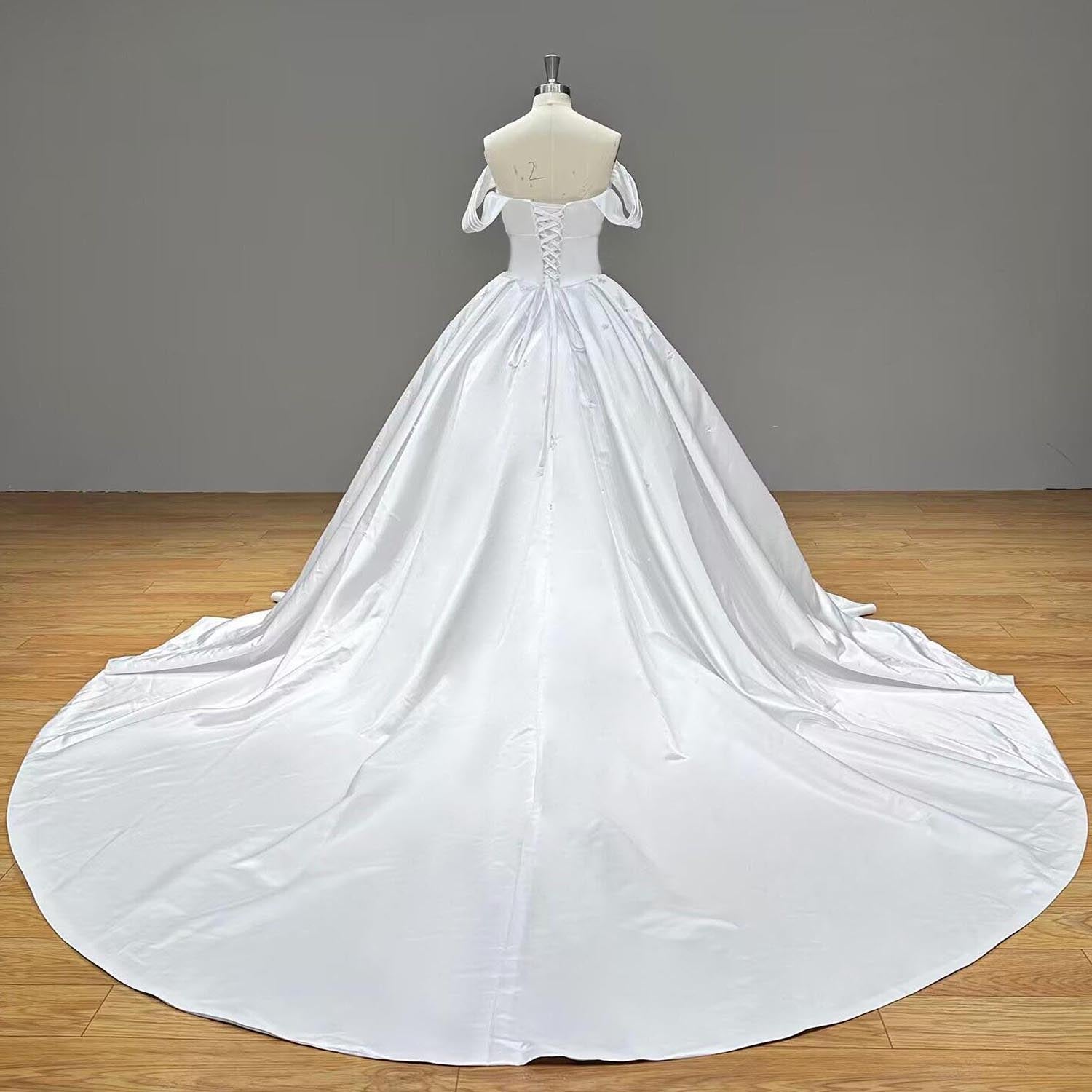 Full-length studio back view of a white satin ball gown wedding dress showcasing the clean lines of an expansive circular cathedral train.