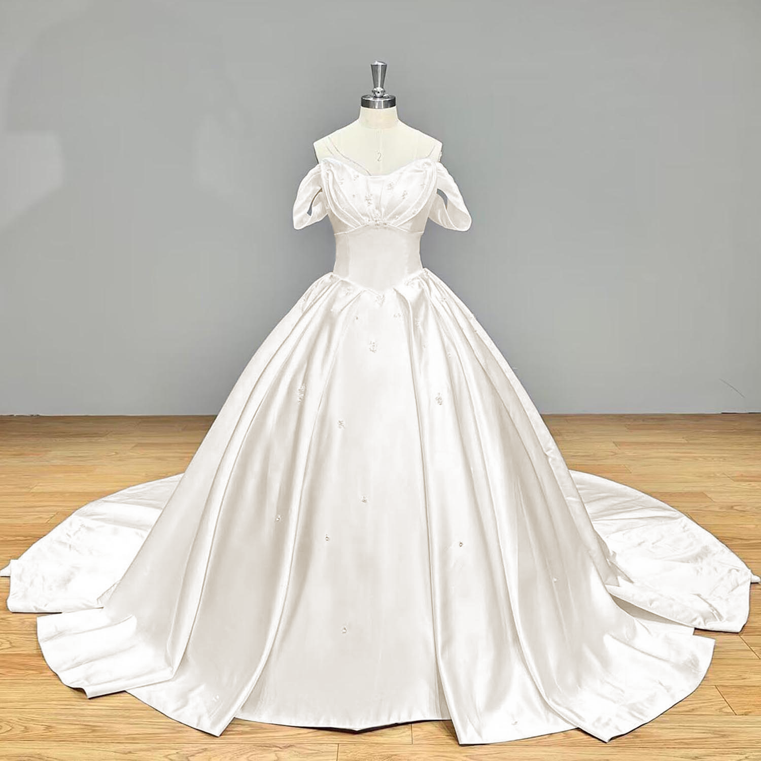 Full front view of an ivory satin ball gown wedding dress on a mannequin, emphasizing the clean, unembellished princess skirt layout under warm lighting.