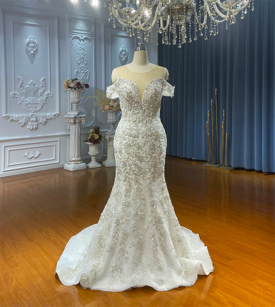 Form-fitting off-the-shoulder mermaid wedding dress without the overskirt, illustrating the elegant trumpet silhouette and detailed silver-toned lace embroidery from the neckline to the floor.