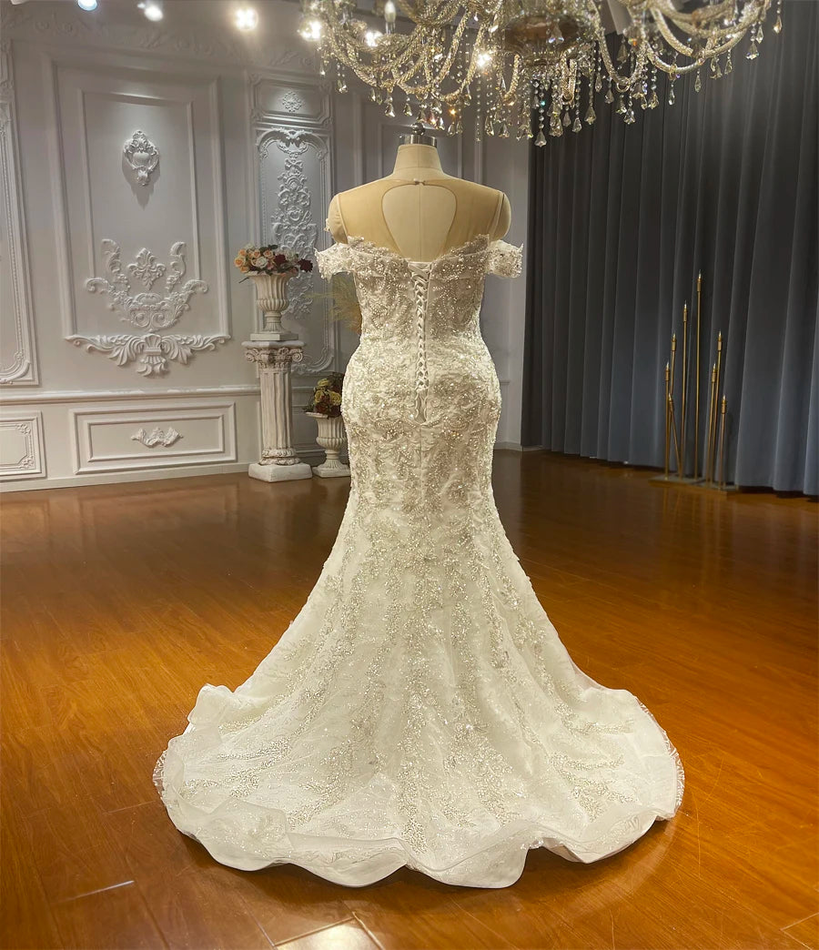 Back view of the beaded mermaid bridal gown alone, featuring an adjustable corset-style back and a delicate chapel-length train with scalloped lace borders.