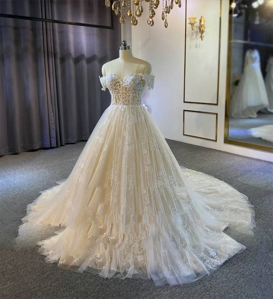 Three-quarter view of an elegant A-line wedding party dress with off-the-shoulder sleeves and a shimmering, layered tulle skirt.