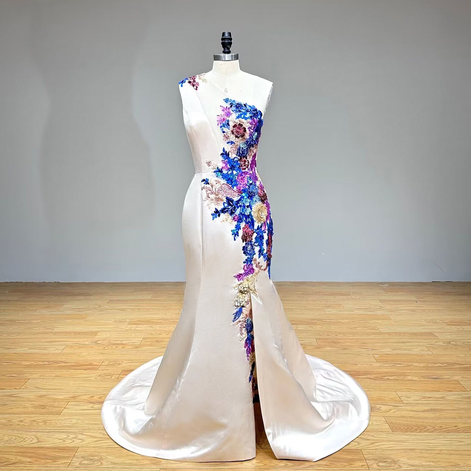 Studio display of a premium one-shoulder 3D floral formal dress with a dramatic side slit skirt.
