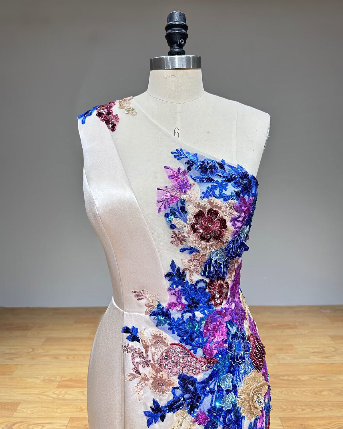Macro detail shot of the handcrafted 3D textile flowers, crystal bead clusters, and fine embroidery along the neckline of a couture evening gown.