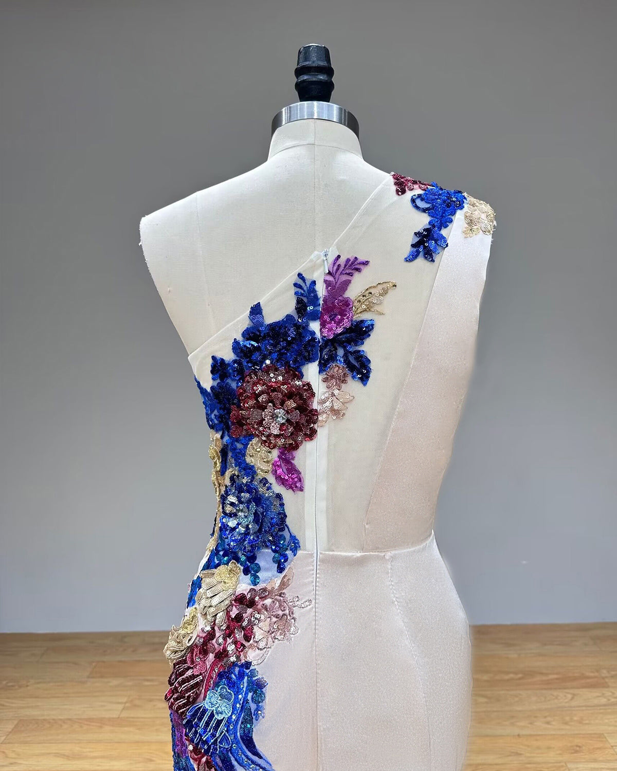 Close-up back view of a formal evening gown highlighting a secure hidden zipper back closure and delicate lace-trimmed asymmetric shoulder strap details.