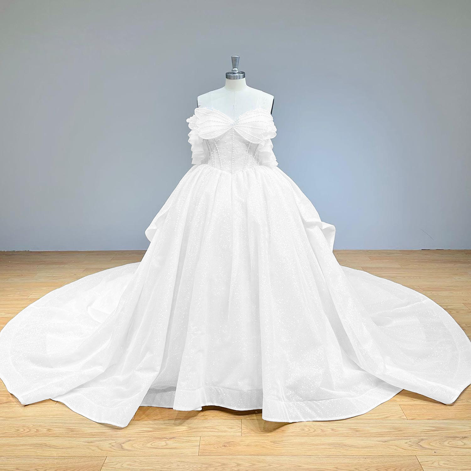 Wide full front studio view of a bright, sparkling pearl bow glitter ball gown wedding dress on a mannequin, perfectly capturing the elegant off-shoulder design and wide sweeping train.