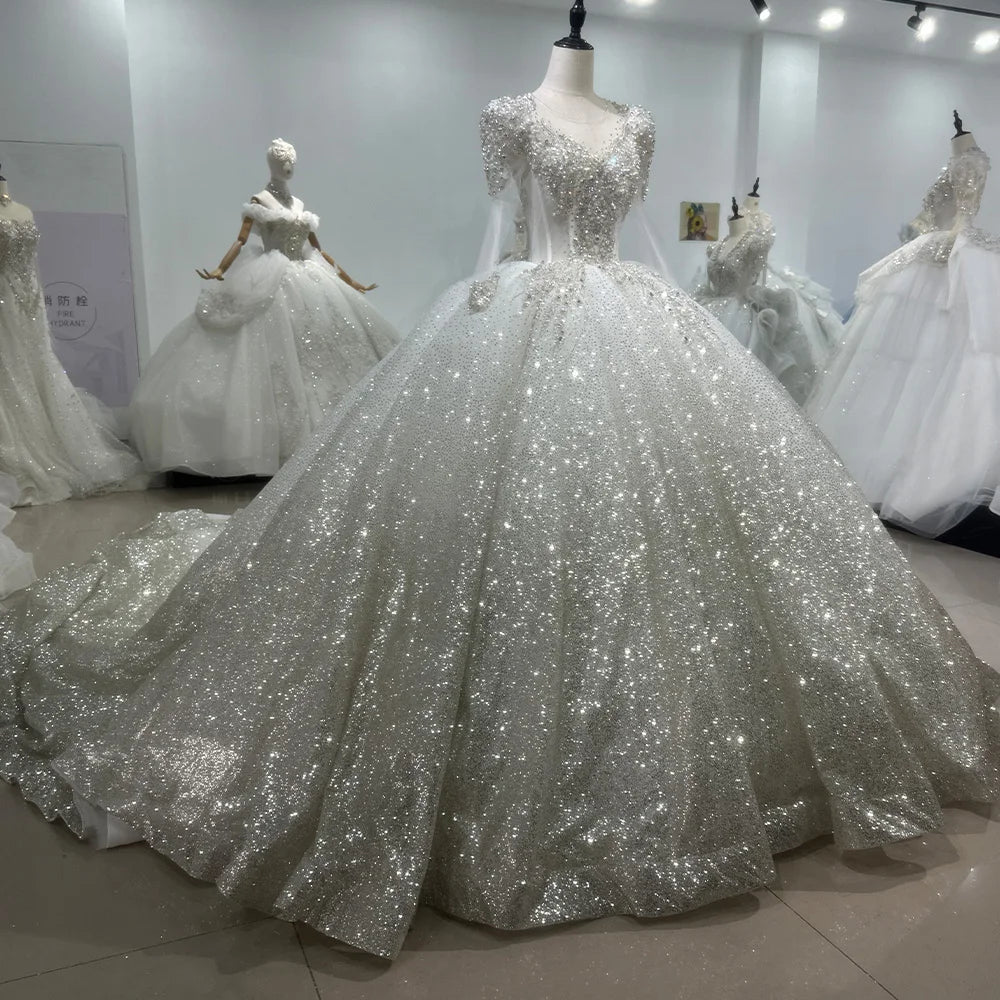 Full back view of a long sleeve ball gown wedding dress on a mannequin, highlighting the dramatic backless cutout design and a sweeping cathedral train.