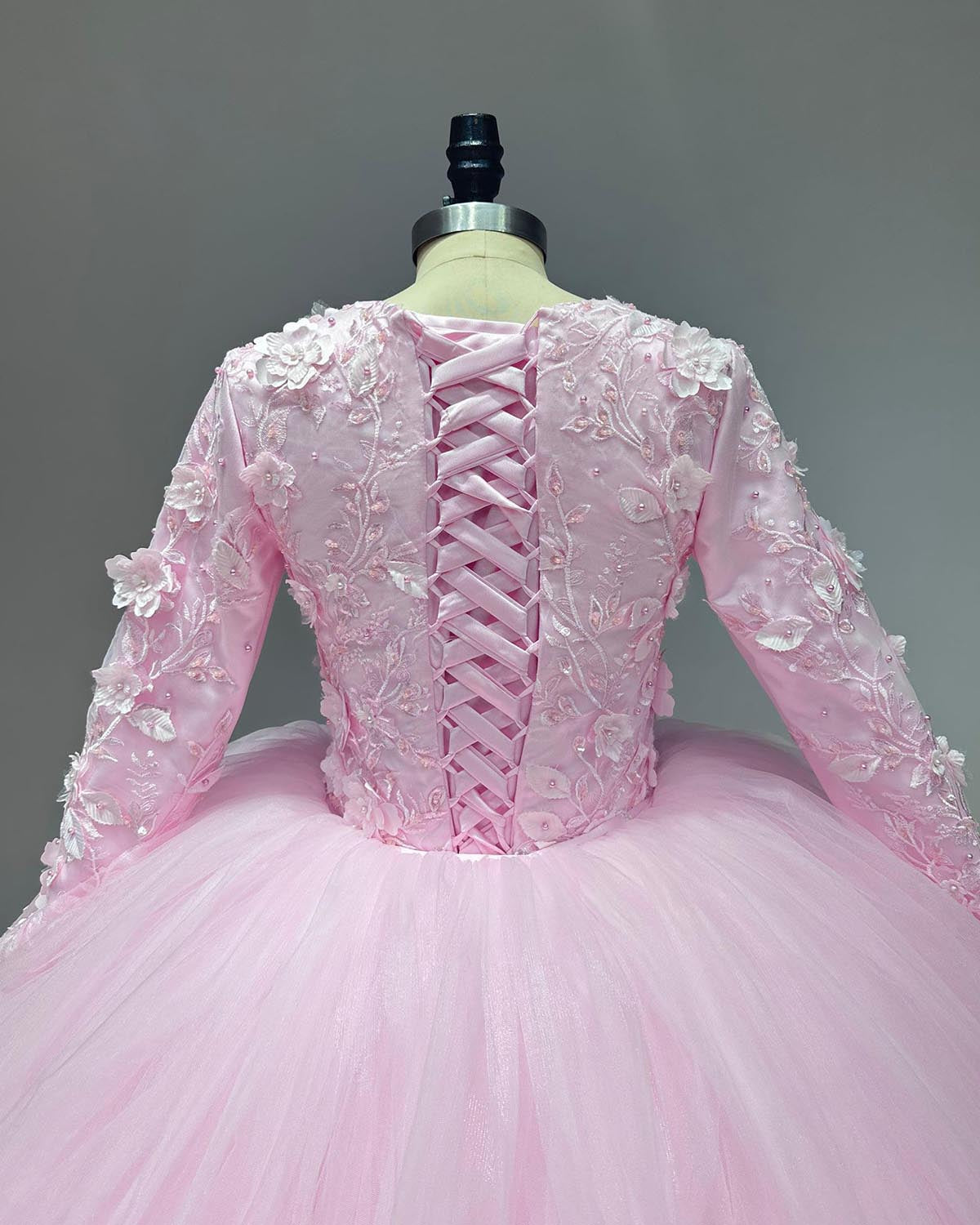 Detailed back view of a pink bridal bodice showcasing a classical satin ribbon lace-up corset closure and delicate 3D floral appliques scattered along the shoulders and sleeves.