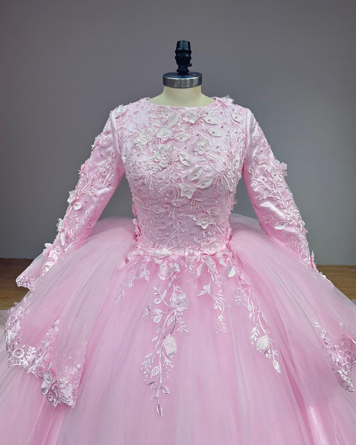 Close-up front view of a high-neck pink wedding gown bodice completely covered in handmade 3D floral elements and fine pearl beadwork.