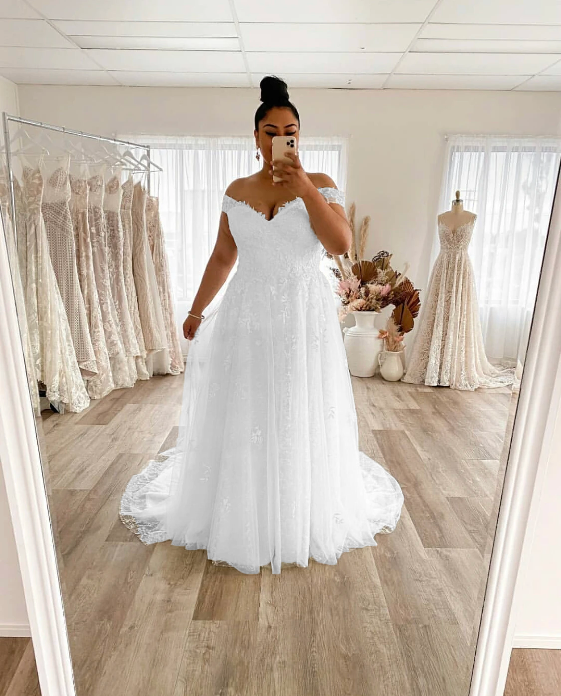 Close-up portrait of a plus-size bride in an off-shoulder, lace applique A-line wedding dress.
