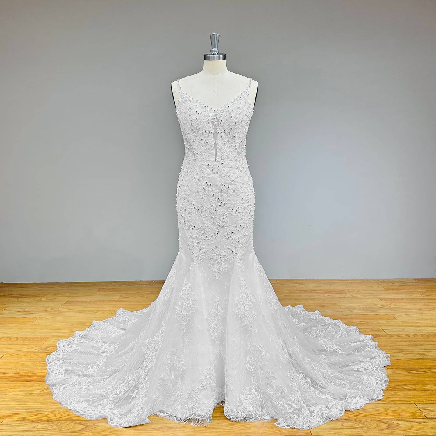 Classic princess-style crystal mermaid wedding dress with an embellished V-neckline bodice and an airy flared trumpet skirt on a mannequin.