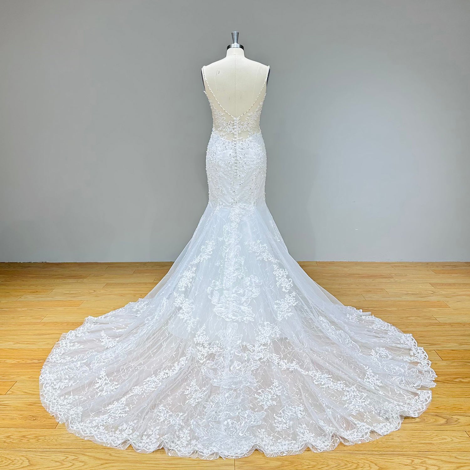 Full back view of a lace trumpet wedding dress showcasing a sheer illusion low back and a dramatic circular chapel train with intricate lace borders.