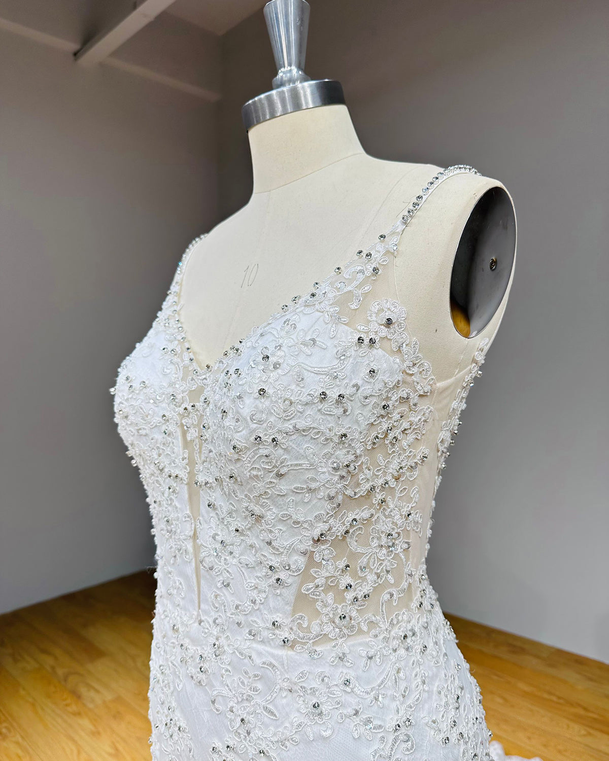 Side angle close-up of a luxury wedding gown bodice emphasizing the sheer mesh side cutouts, structured cups, and dense rhinestone embellishments.