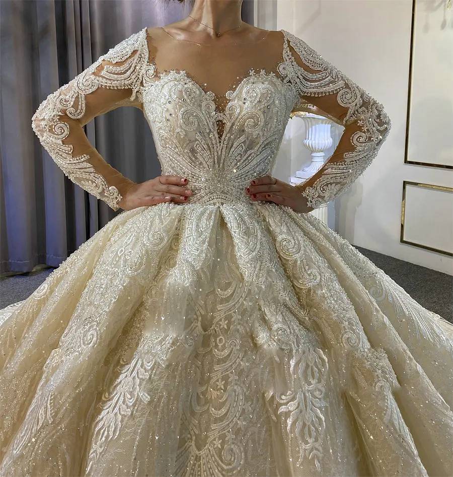 Close-up front view of the luxury princess puffy ball gown wedding dress, emphasizing the intricate beadwork on the bodice, the illusion sweetheart neckline, and elegant long sleeves.