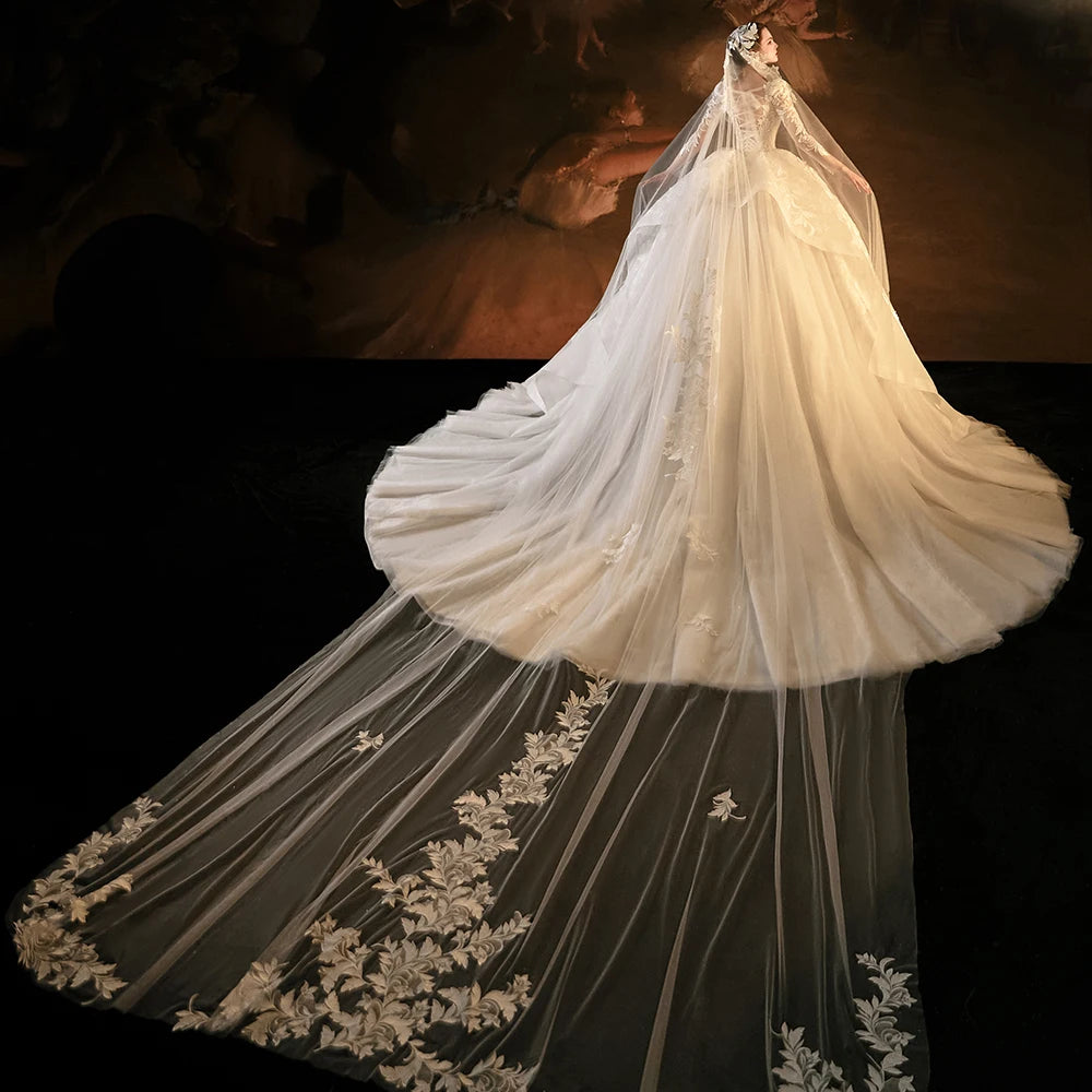 Close-up of a luxury bridal gown bodice highlighting the unique square neckline, intricate hand-beaded silver crystals, and sheer shimmering long sleeves.