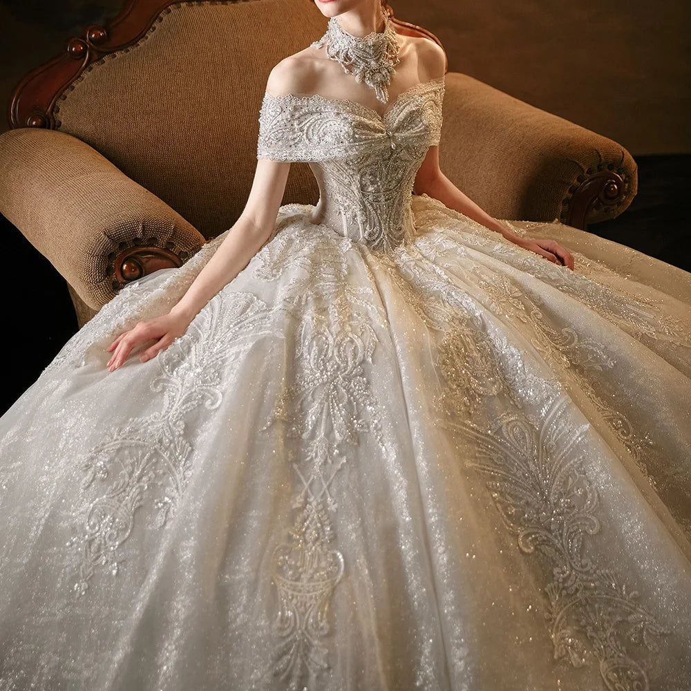 Close-up shot of a luxury wedding dress bodice highlighting the intricate crystal beadwork, sweetheart neckline, off-the-shoulder lace straps, and matching high-neck choker.