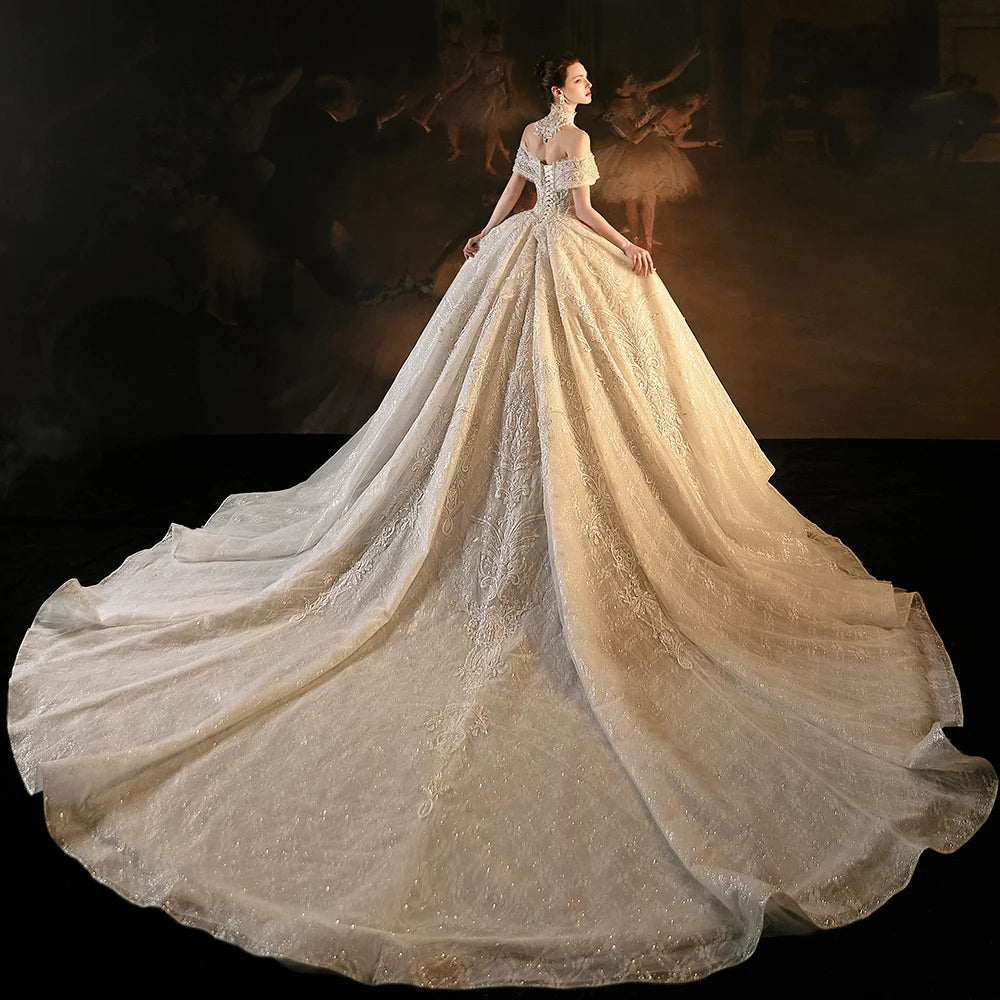 Full back view of a princess ball gown wedding dress showcasing the elegant lace-up corset closure, off-the-shoulder straps, and a sweeping, voluminous sequined skirt.