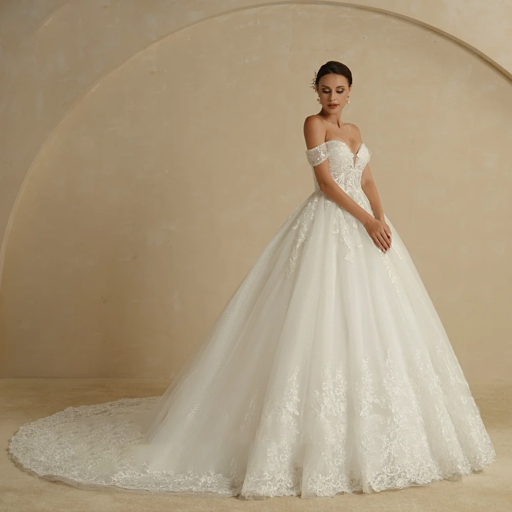 A full-length side profile of an ivory ball gown wedding dress, highlighting the voluminous glitter skirt, court train, and elegant lace applique.