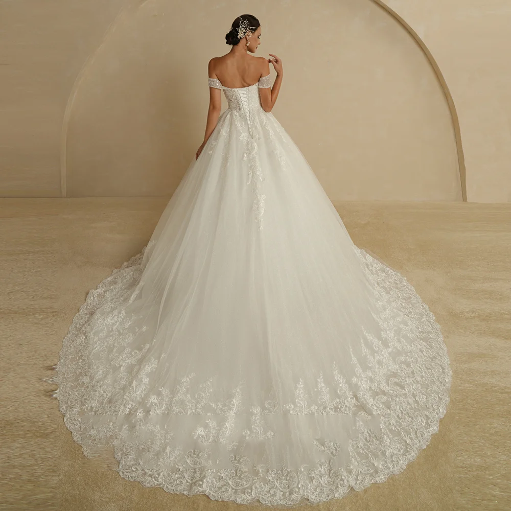 Back view of an ivory vintage wedding ball gown, emphasizing the corset back, long court train, and delicate lace embroidery details.