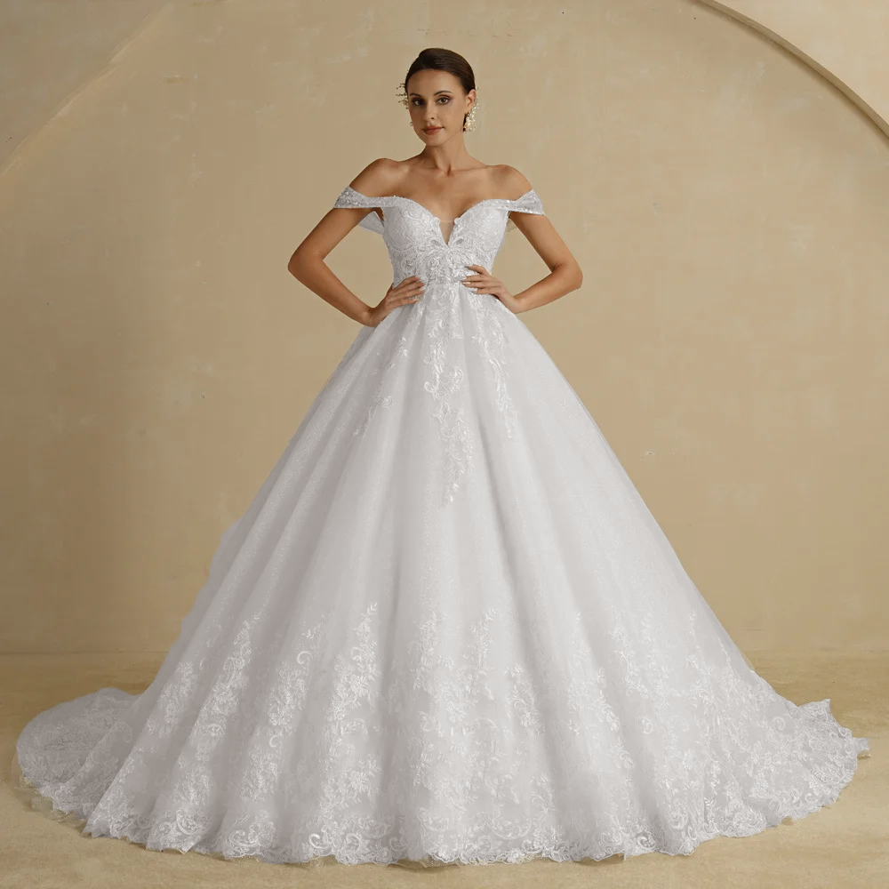 A studio portrait of a bride in an ivory ball gown wedding dress, featuring a sweetheart neckline and beautiful lace appliques on the skirt.