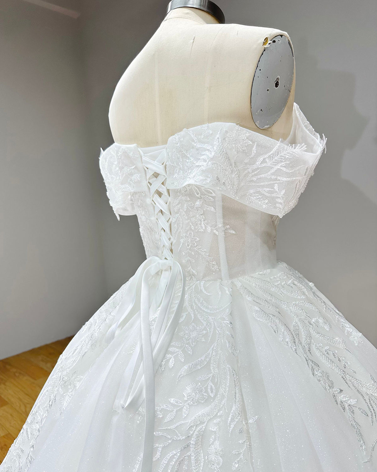 Close-up back shot of a wedding dress corset lace-up closure framed by sheer illusion panels and shimmering silver thread embroidery.