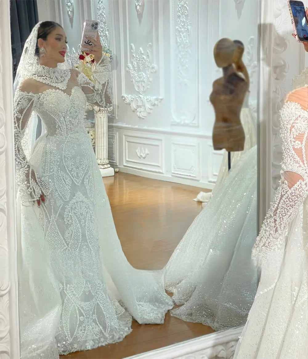 Mirror selfie of a bride trying on the elegant lace mermaid wedding dress, highlighting the flattering form-fitting silhouette, high-neck design, and exquisite beaded lace details.