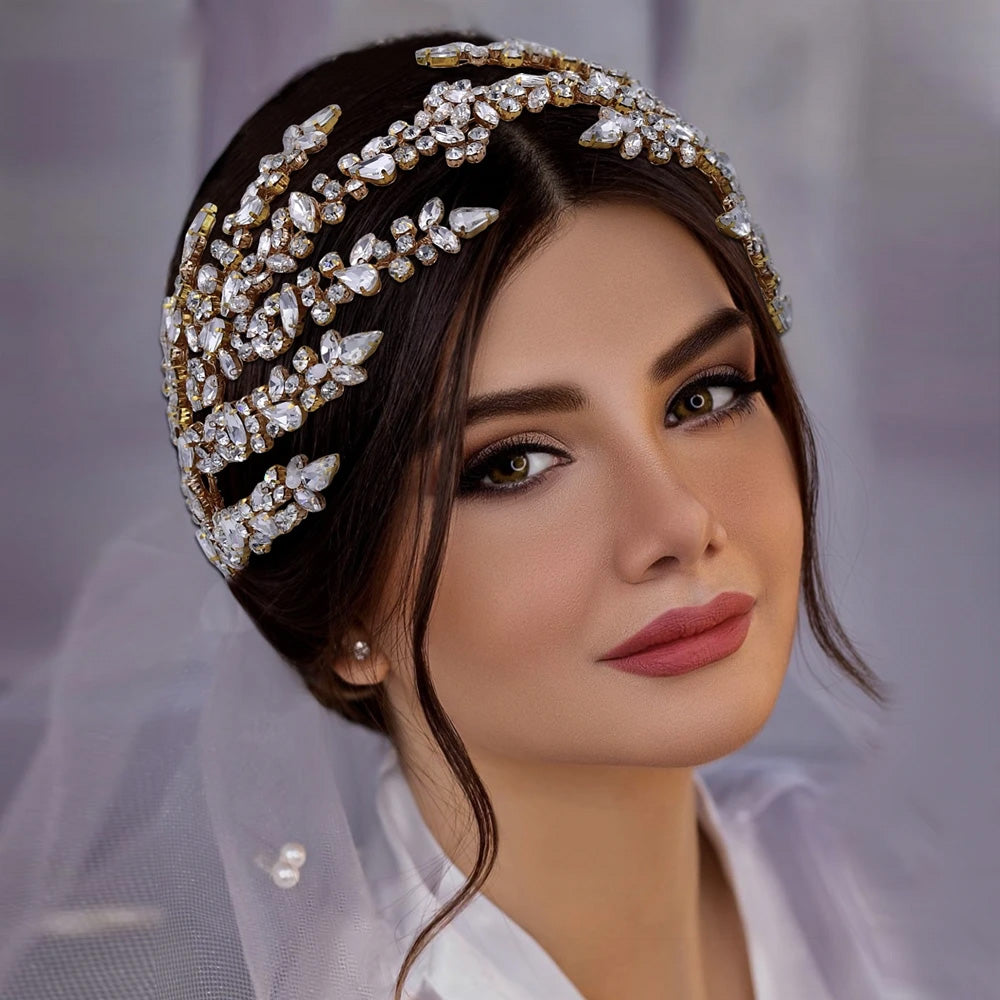 Front portrait of a model showcasing a luxury gold-plated wedding tiara band designed with shimmering marquise-cut crystal leaves.