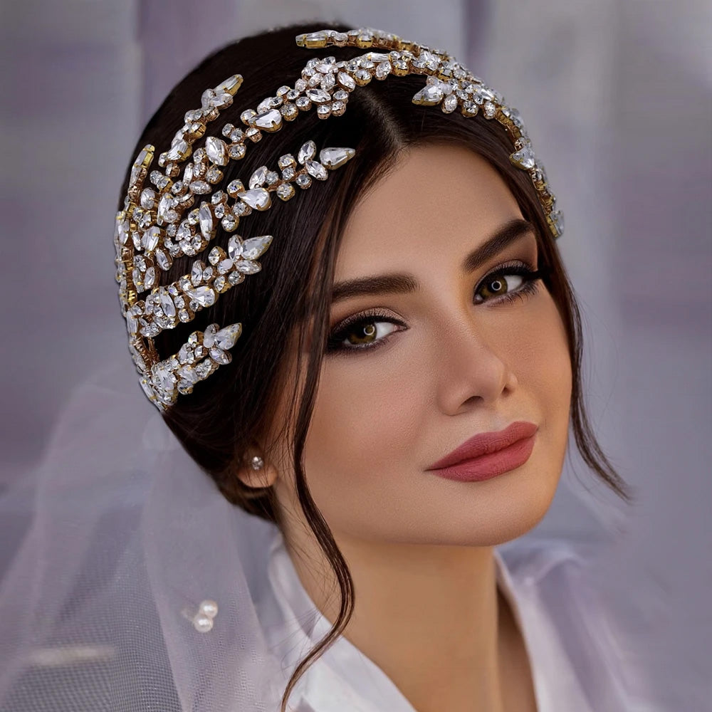 Close-up portrait variant of a brunette bride looking straight forward, showcasing the gold-plated crystal rhinestone leaf branch crown.