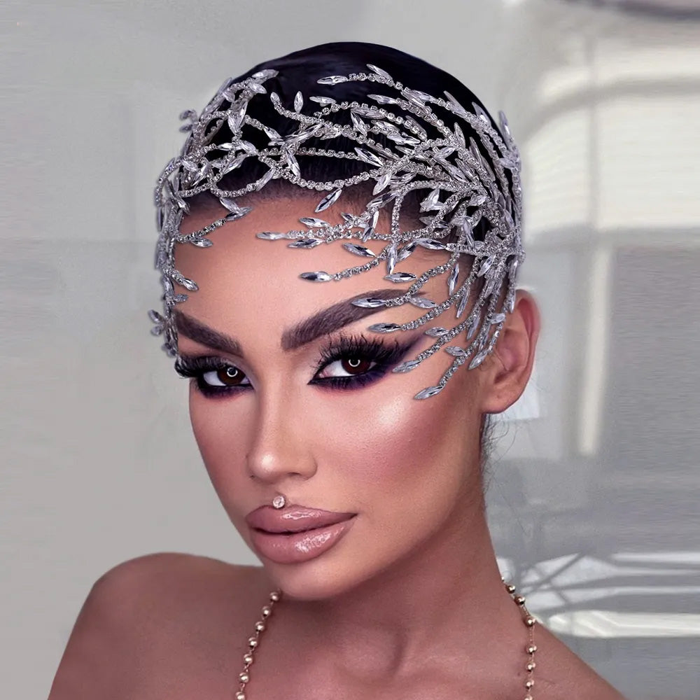 Symmetrical front portrait of a glamour model featuring a dramatic silver crystal bridal tiara designed with fine sweeping leaf vines across the forehead.