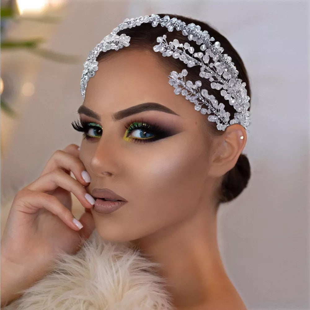 Side view profile of a model featuring a delicate beaded silver bridal headpiece crafted with intertwined crystal branches and tiny white pearls.