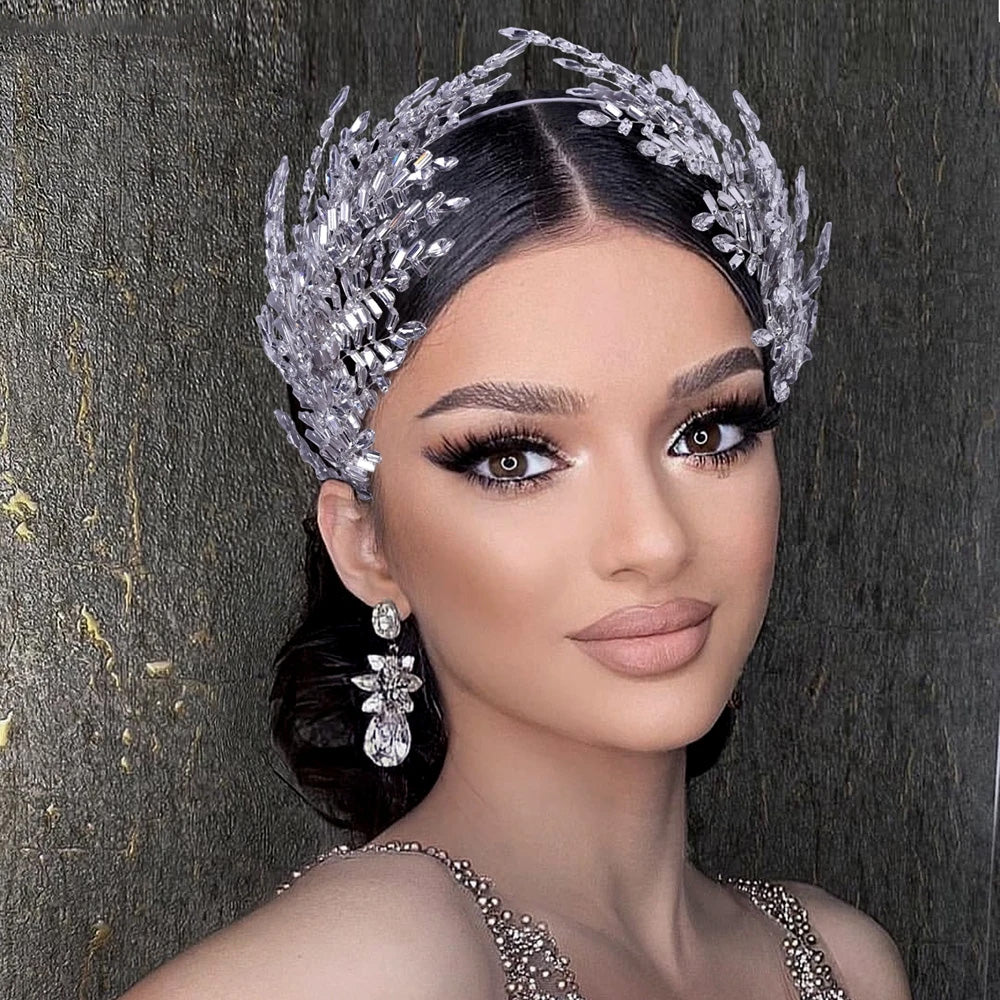 Symmetrical portrait of a bride wearing a high-set designer rhinestone bridal tiara with intricate silver leaf arches, styled with matching crystal drop earrings.