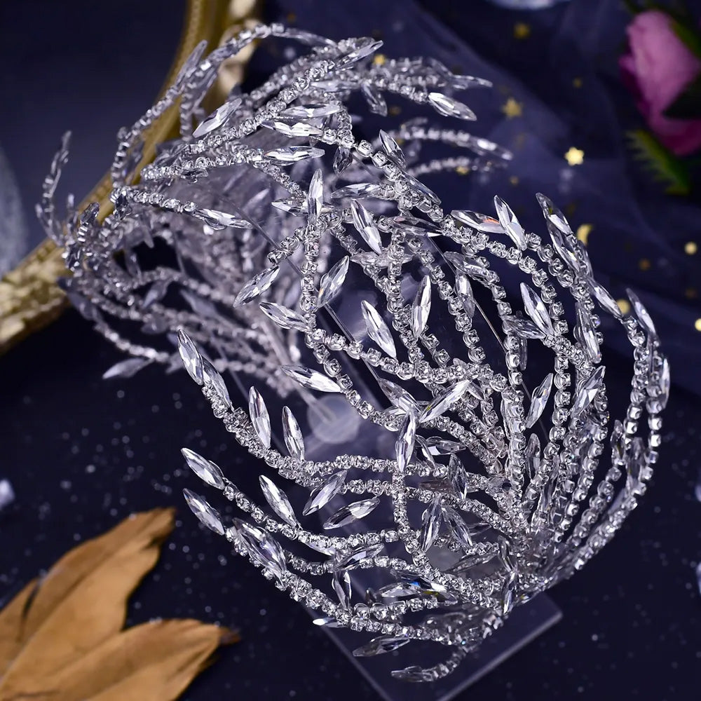 Close-up top view of a luxury silver rhinestone bridal headpiece showing intricate floral vine structures crafted with clear crystal petals.